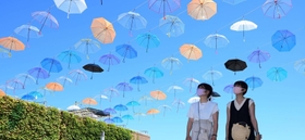 青空にきらきら輝くカラフルな傘＝淡路市夢舞台、国営明石海峡公園