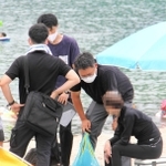 切浜海水浴場近くの岩場でサザエやアワビを採取した女性（右）を聴取する海上保安官ら＝豊岡市竹野町切浜（画像の一部を加工しています）