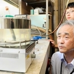 アンモニア化合物の水溶液から水素を取り出す実験を見守る森下政夫教授（手前）＝姫路市書写、兵庫県立大