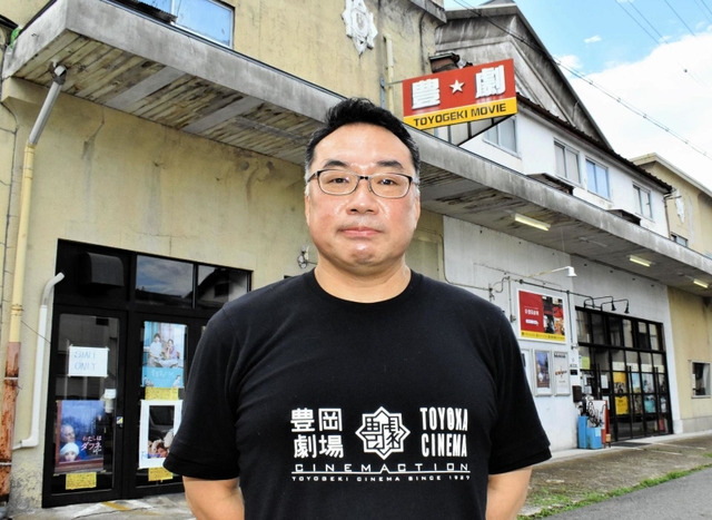 築９４年になる豊岡劇場の前に立つ石橋秀彦代表＝豊岡市元町