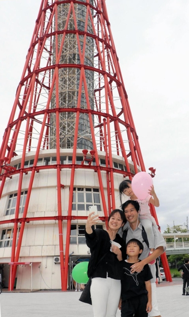 神戸ポートタワーを背に記念写真を撮る家族＝２６日午後、神戸市中央区波止場町