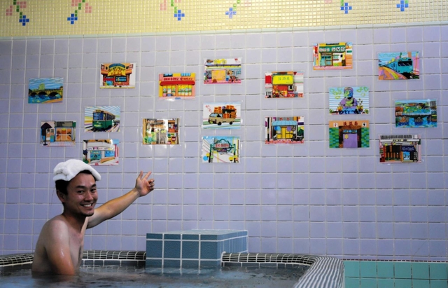 湯船に漬かって展示作品を紹介する田岡和也さん＝神戸市兵庫区笠松通６、笠松湯