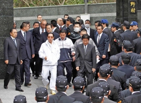 工藤会関係先を家宅捜索する福岡県警捜査員と野村悟被告（中央左、白色の服装）