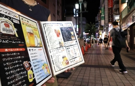 アルコールのメニューを広げて通りで客を呼び込む店員＝９日夜、神戸市中央区（撮影・鈴木雅之）
