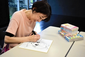 ボイシーのリスナープレゼント用にサインを書くひうらさとるさん＝豊岡市内