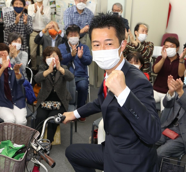 選挙区を駆け回った自転車にまたがり当選を喜ぶ井坂信彦氏＝神戸市中央区八幡通４（撮影・小林良多）