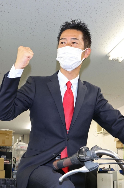 選挙区を駆け回った自転車にまたがり当選確実を喜ぶ井坂信彦氏＝神戸市中央区八幡通４（撮影・小林良多）