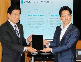 小泉進次郎前環境省からタブレットを引き継ぐ山口壮新環境相（左）＝東京都千代田区