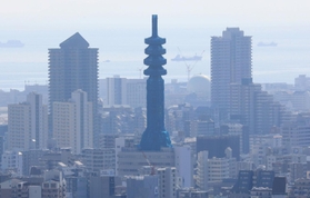 工事のためネットで覆われ、シルエットが丸みを帯びた電波塔。ビル群の中の仏塔のよう＝神戸市中央区のビーナスブリッジから