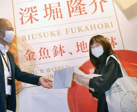 １万人目の来場者として記念品を受け取る高倉那莉亜さん（右）＝神戸市東灘区向洋町中２、神戸ファッション美術館