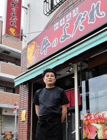 掛け替えたばかりの店名看板の前で新事業への挑戦を語る太田直さん＝神戸市兵庫区上沢通２