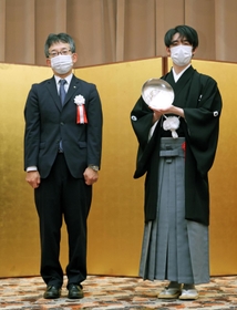 第６２期王位就位式で王位杯を手にする藤井聡太王位。左は日本将棋連盟の佐藤康光会長＝２８日午後、東京都千代田区（代表撮影）