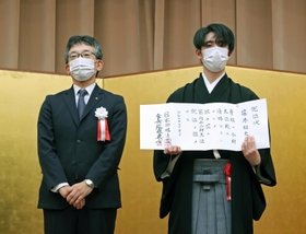 第６２期王位就位式で、就位状を手にする藤井聡太王位。左は日本将棋連盟の佐藤康光会長＝２８日午後、東京都千代田区（代表撮影）