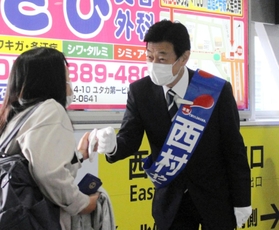 駅構内で支援者らとグータッチを交わす西村氏＝２１日、明石市小久保２