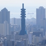 工事のためネットで覆われ、シルエットが丸みを帯びた電波塔。ビル群の中の仏塔のよう＝神戸市中央区のビーナスブリッジから