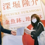 １万人目の来場者として記念品を受け取る高倉那莉亜さん（右）＝神戸市東灘区向洋町中２、神戸ファッション美術館