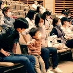 童謡「むすんでひらいて」で体を動かしながら、歌を楽しむ参加者＝うはらホール