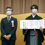 第６２期王位就位式で、就位状を手にする藤井聡太王位。左は日本将棋連盟の佐藤康光会長＝２８日午後、東京都千代田区（代表撮影）