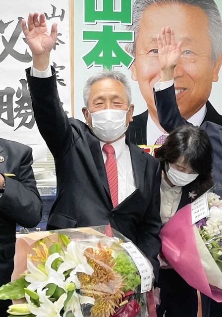 たつの市長選で当選確実の報道を受け、万歳する現職・山本実氏＝たつの市龍野町富永の事務所