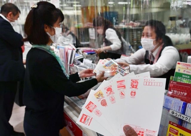売り出された２０２２年用年賀はがき（手前）を購入する人たち＝１日午前、神戸市中央区栄町通６、神戸中央郵便局（撮影・坂井萌香）