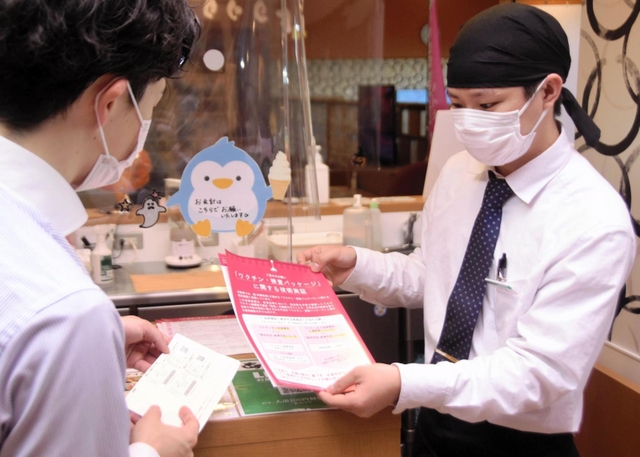 ワクチン接種済証を確認する飲食店員（右）＝１日午後、神戸市長田区南駒栄町