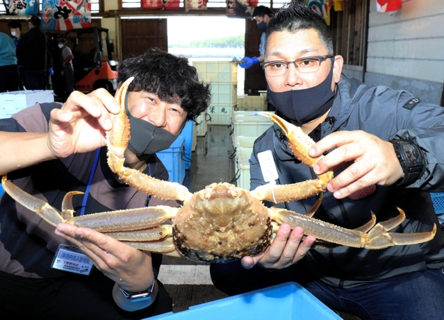 初競りの１匹目を２０万円で落札した植村良輔さん（右）＝６日午後、兵庫県新温泉町芦屋、浜坂漁港