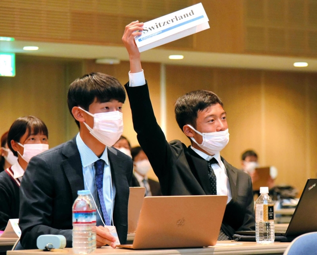 プラカードを掲げて意見を表明する灘高校チーム＝淡路市夢舞台、淡路夢舞台国際会議場