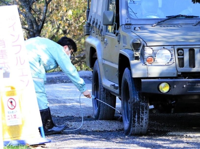 養鶏場から出る自衛隊車両を消毒する県職員＝１７日午前、姫路市内（撮影・大山伸一郎）