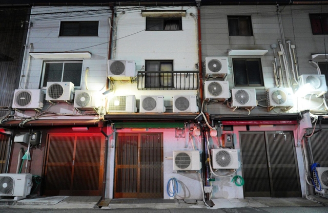 店の壁には大量のエアコン室外機。廃業した店の室外機は撤去が進められている。パトカーの赤色灯で壁がうっすら赤い＝５日夜、尼崎市神田南通３