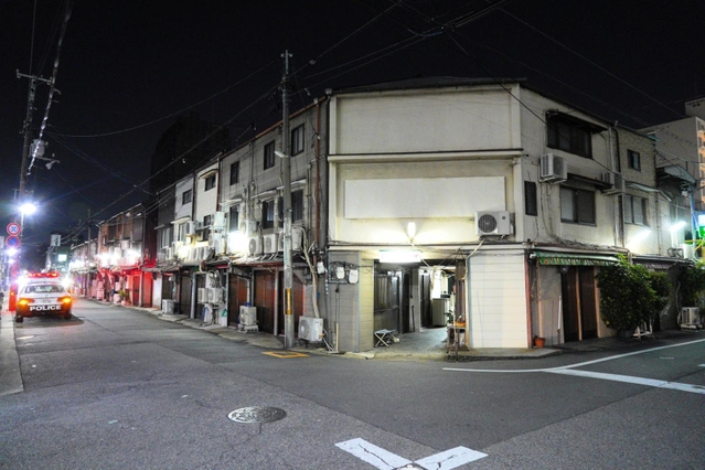日が暮れても、人気のないかんなみ新地。店先ではパトカーが赤色灯を回して警戒している＝５日夜、尼崎市神田南通３