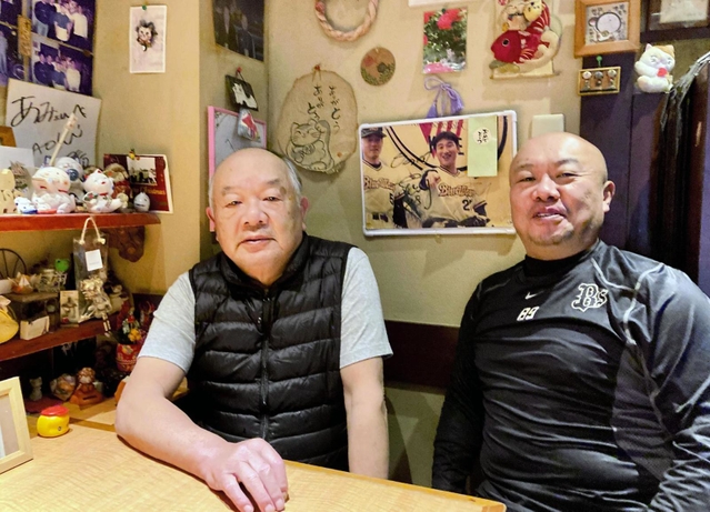 ２５年前の優勝パレードの中嶋監督の写真を見ながら談笑する木下大輔さん（右）と父の一夫さん＝神戸市須磨区大田町２