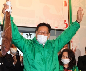 当選確実となり、タイを掲げる関芳弘氏＝神戸市須磨区大池町２（撮影・吉田敦史）