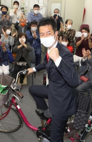 選挙区を駆け回った自転車にまたがり、当選を喜ぶ井坂信彦氏＝神戸市中央区八幡通４（撮影・小林良多）