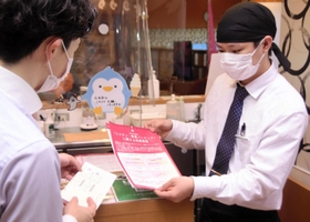 ワクチン接種済証を確認する飲食店員（右）＝１日午後、神戸市長田区南駒栄町
