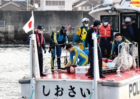 要救助者に見立てた人形を海から引き揚げ、心肺蘇生を試みる警察官と海上保安官ら＝２日午前、南あわじ市沼島