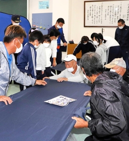 沼島小であった避難所の設営訓練で、簡易ベッドを組み立てる住民ら＝南あわじ市沼島