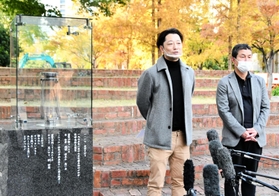 東遊園地に設置されているガス灯「１・１７希望の灯（あか）り」のそばで来年の追悼行事について説明する実行委員長の藤本真一さん（左）ら＝神戸市中央区