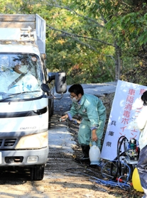 養鶏場から出る自衛隊車両を消毒する県職員＝１７日午前、姫路市内（撮影・大山伸一郎）