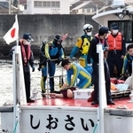 要救助者に見立てた人形を海から引き揚げ、心肺蘇生を試みる警察官と海上保安官ら＝２日午前、南あわじ市沼島