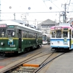 神戸市電から移籍した広島電鉄で路面電車として活躍する（右から）「１１５６号」と、期間限定で車体に市電時代のオレンジ線が再現された「５８２号」＝広島市内（広島電鉄提供）