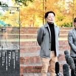 東遊園地に設置されているガス灯「１・１７希望の灯（あか）り」のそばで来年の追悼行事について説明する実行委員長の藤本真一さん（左）ら＝神戸市中央区
