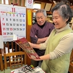ヴィッセル神戸の新聞記事の切り抜きなどを懐かしそうに眺める釜須一昭さん（奥）と妻保美さん＝神戸市兵庫区小松通３