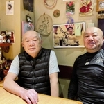 ２５年前の優勝パレードの中嶋監督の写真を見ながら談笑する木下大輔さん（右）と父の一夫さん＝神戸市須磨区大田町２