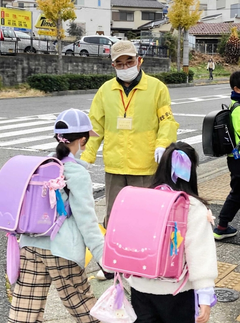 「おはよう、気を付けてな」と声を掛ける藤田和彦さん。１５年以上、登校時の子どもたちを見守ってきた＝神戸市垂水区