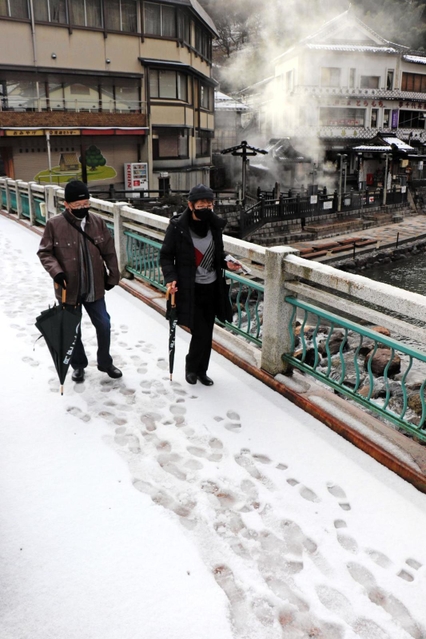 雪の積もった温泉橋を歩く観光客＝１８日午前８時５０分、新温泉町湯、湯村温泉