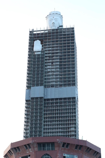 高層ビルの中に巨像？　首付近まで工事用の足場に覆われた観音像＝２１日、淡路市釜口