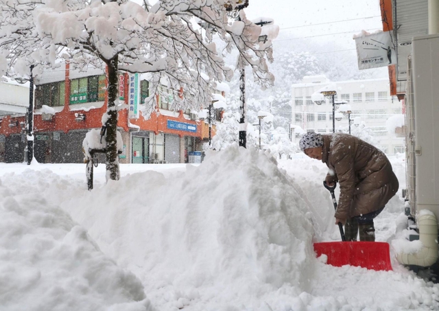 降り続く雪の中、雪かきをする女性＝２７日午前８時５分、朝来市和田山町東谷（撮影・竜門和諒）