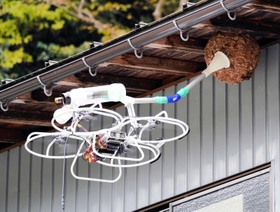 ラッパ状のノズルで巣から出てきたハチを吸い取って駆除するドローン＝養父市草出（ダスキン提供）
