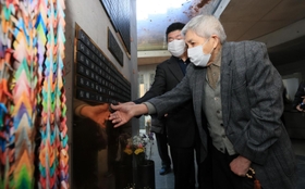 阪神・淡路大震災で妻を亡くして１９９６年に病死した父・田中秀市さんの名前が刻まれた銘板を貼り付ける、長男・田中正裕さん（手前）＝１１日午後、神戸市中央区加納町６（撮影・鈴木雅之）