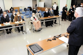 旧優生保護法の被害者支援条例案が可決したことについて、泉房穂市長（右）から報告を受ける小林宝二さん（前列左から２人目）、喜美子さん夫妻＝明石市役所